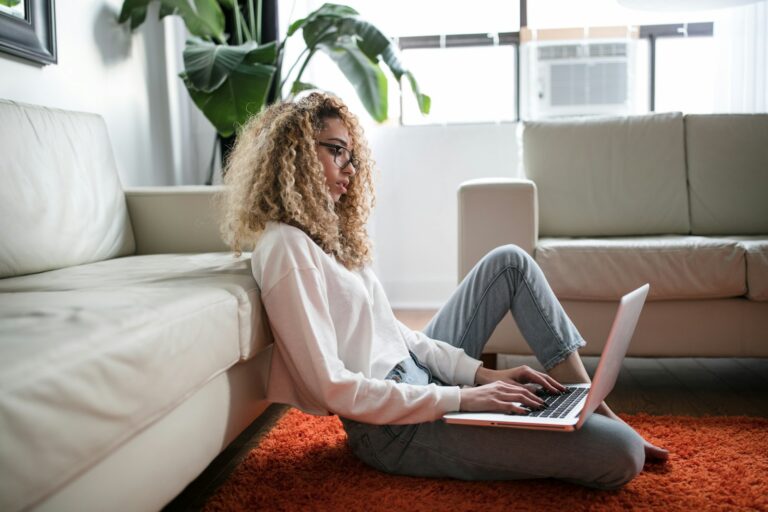 Fiatal nő a nappaliban ülve laptopon böngészi a diákmunka-lehetőségeket